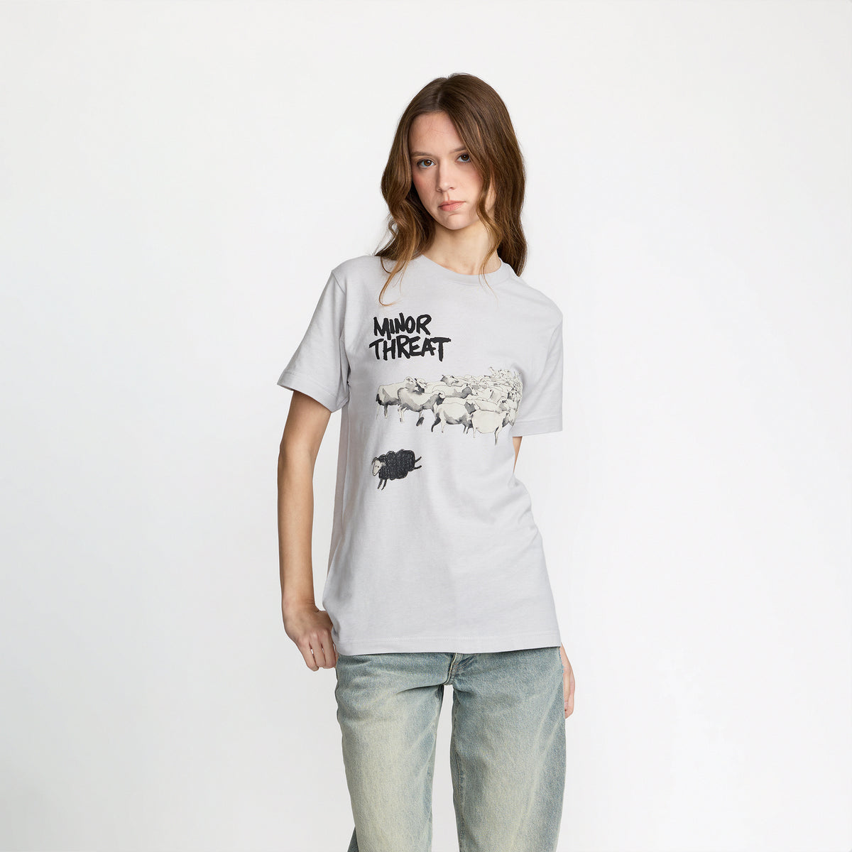 Person wearing a gray t-shirt with &#39;Minor Threat&#39; graphic design on a white background; official band merch by TSURT