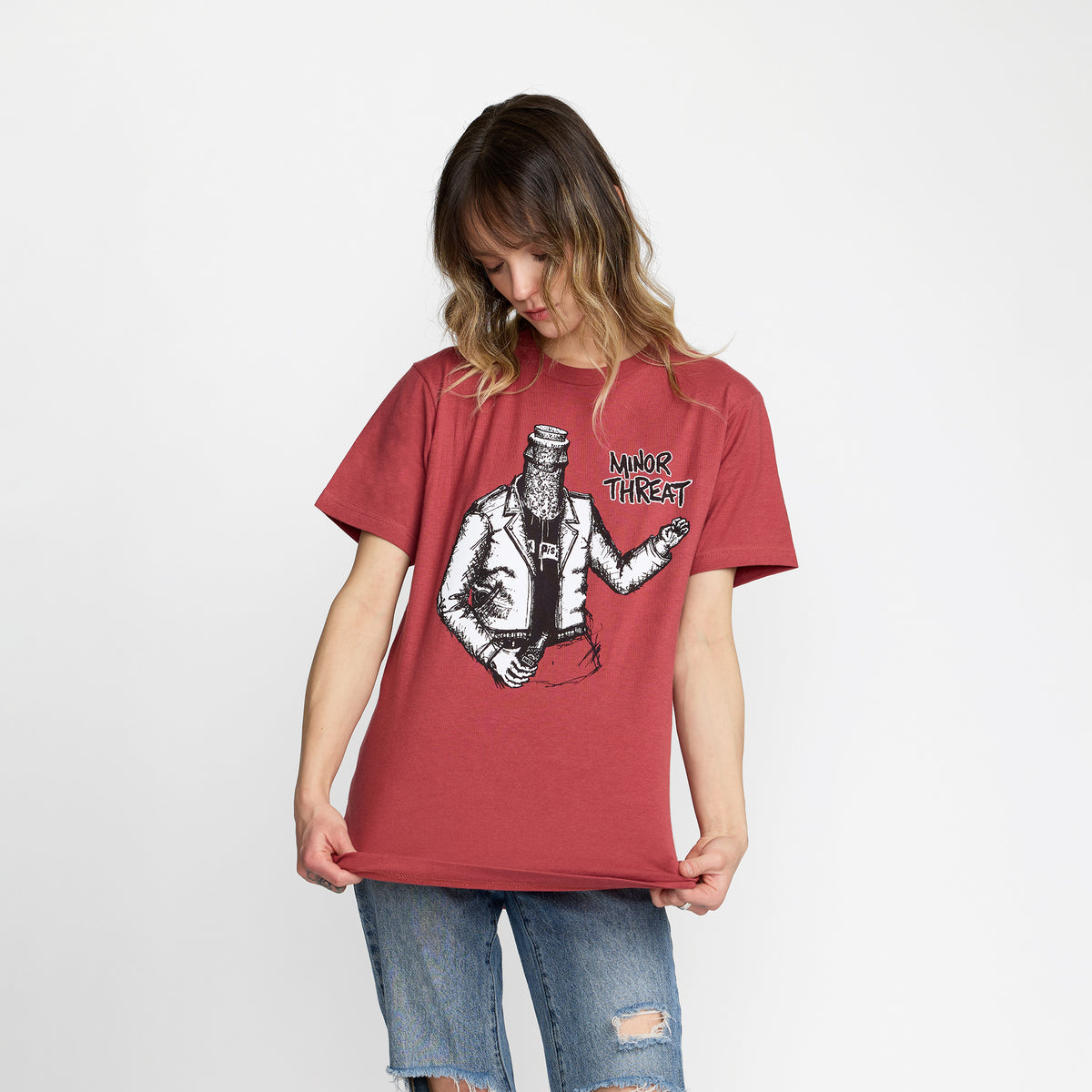 Person wearing a red t-shirt with Minor Threat Bottled Violence Design; official merch produced by TSURT