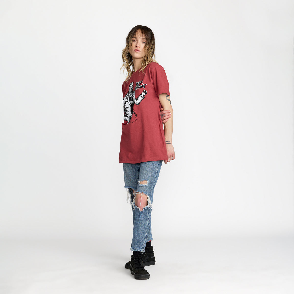 Person wearing a red t-shirt with Minor Threat Bottled Violence Design; official merch produced by TSURT