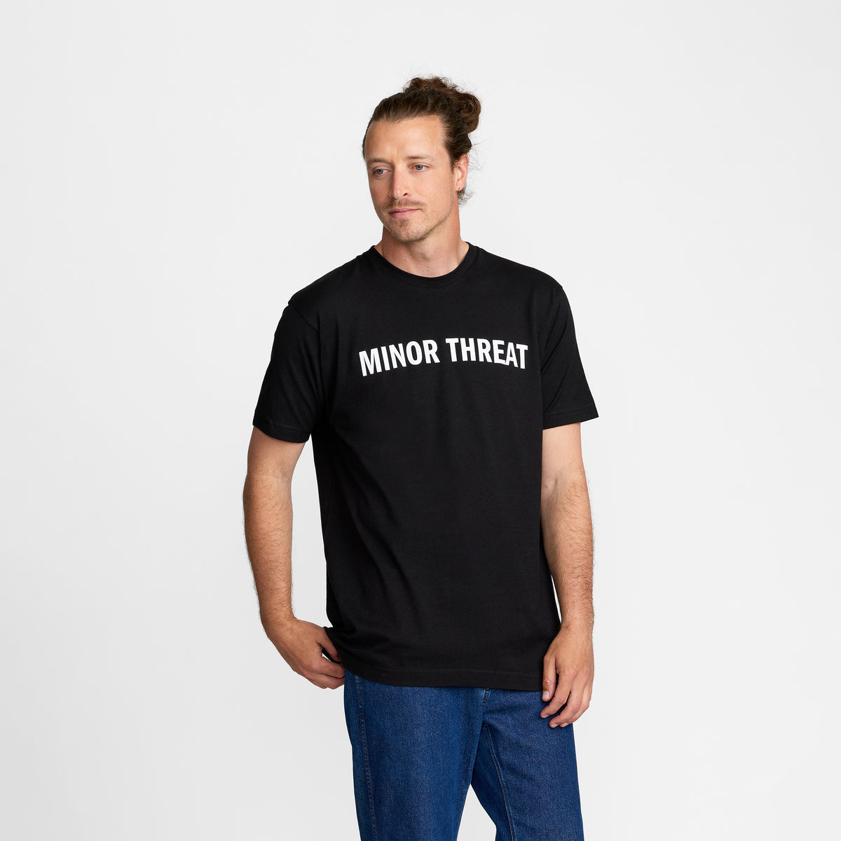 Man wearing a black t-shirt with &#39;MINOR THREAT&#39; text; official Minor Threat merch produced by TSURT