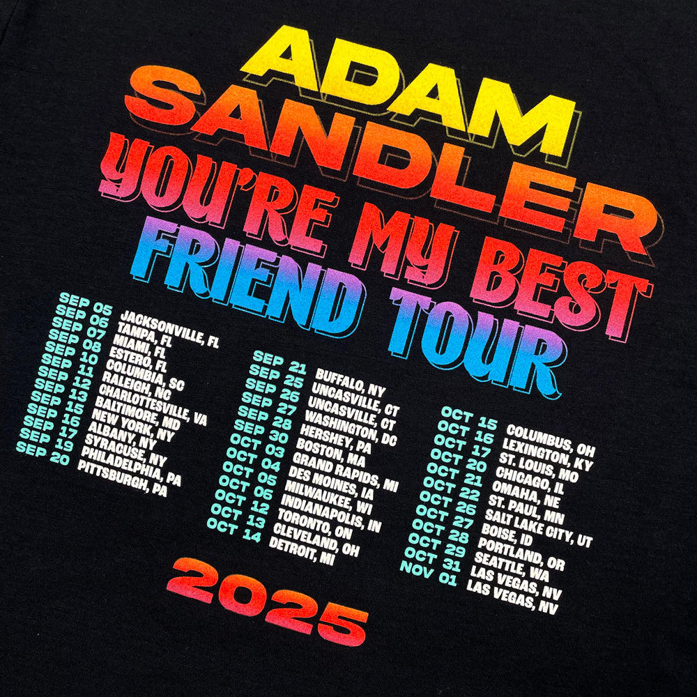 Close up of a black t-shirt form the back  with text reading "Adam Sandler You're My Best Friend Tour" followed by a list of all 2025 tour dates. Below the tour dates is text reading "2025"