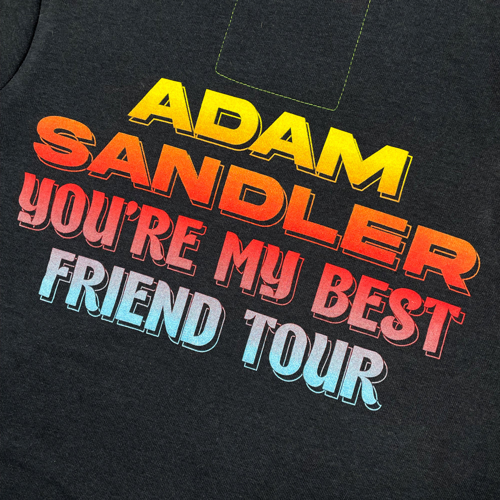 Close up of a black hoodie with colorful text on the back reading "Adam Sandler You're my Best Friend Tour" 