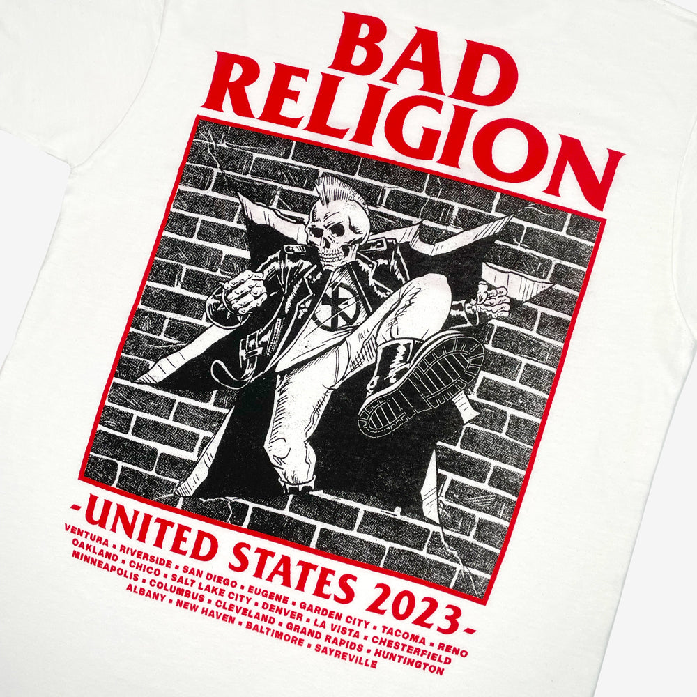 Close up of a white Bad Religion tee back print against white background with graphic of a skeleton kicking through a brick wall and text reading "Bad Religion United States 2023" followed by list of cities from the 2023 tour
