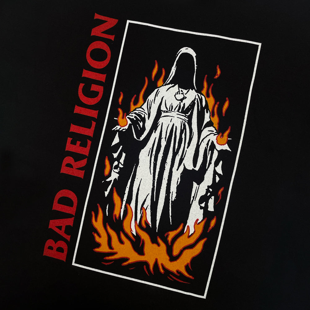 Close up of a black t-shirt with graphic or a nun on fire next to red text reading "BAD RELIGION" 