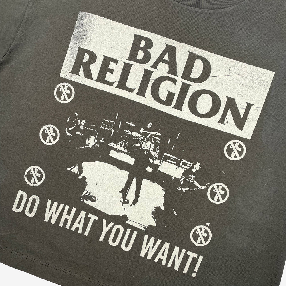 Close up of a green t-shirt with graphic of band playing and text reading "BAD RELIGION DO WHAT YOU WANT!" 