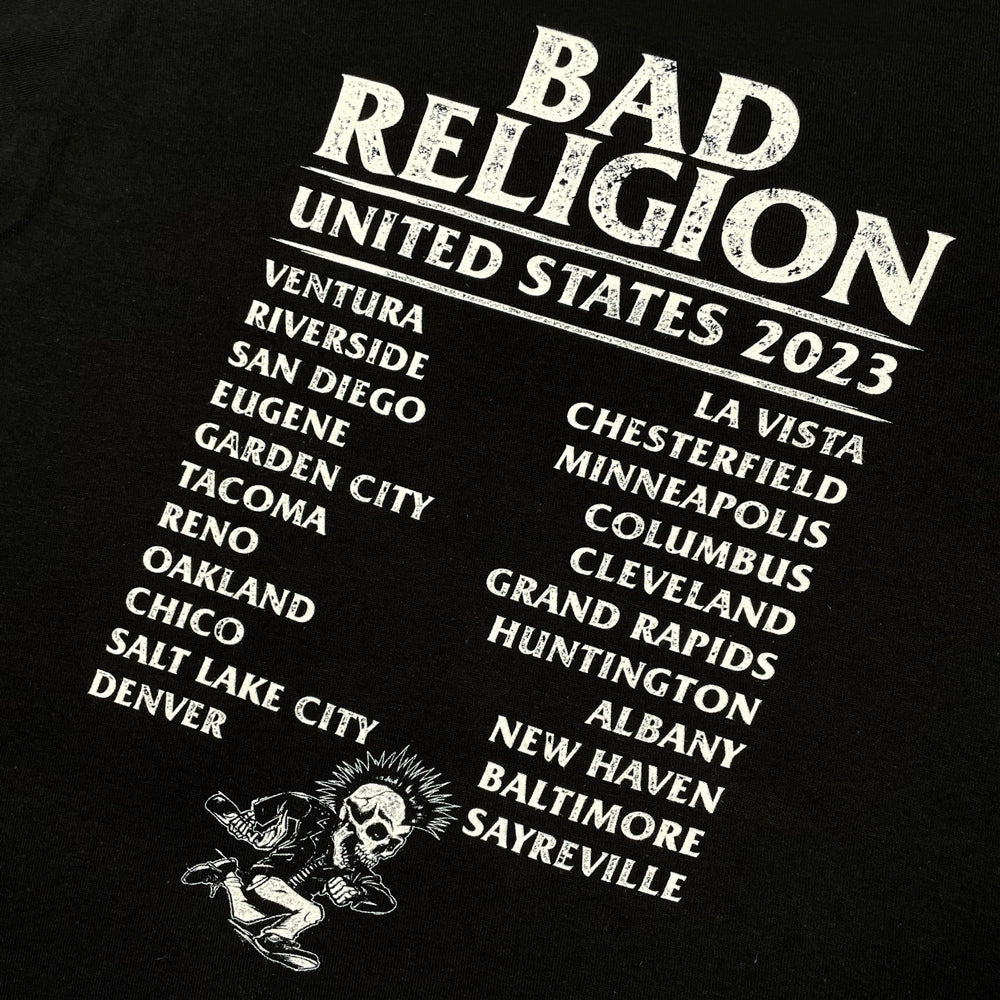 Close up of a black kids tee against a white background with light grey text reading "Bad Religion" followed by text listing all 2023 tour dates. At the bottom is a design of a skeleton with a mohawk and leather jacket running.