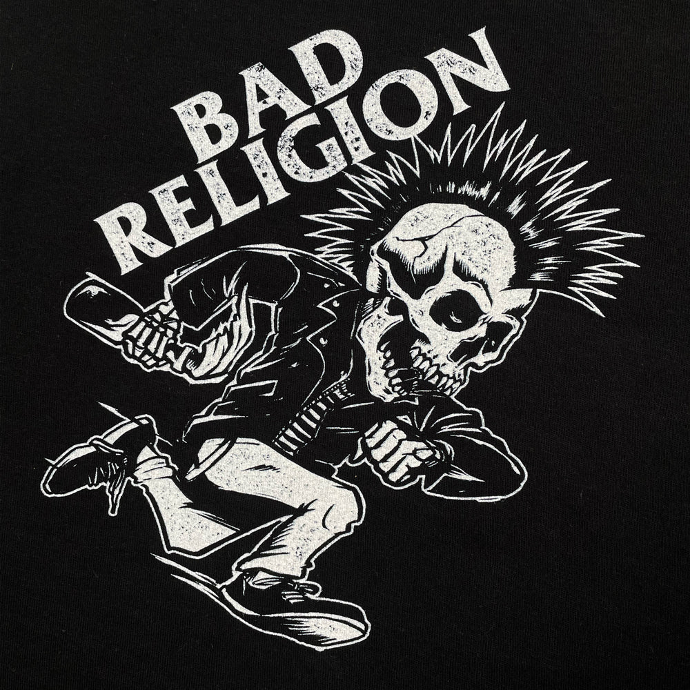 Close up of a black kids tee against a white background with a design of a skeleton with a mohawk and leather jacket running with light grey text reading "Bad Religion"