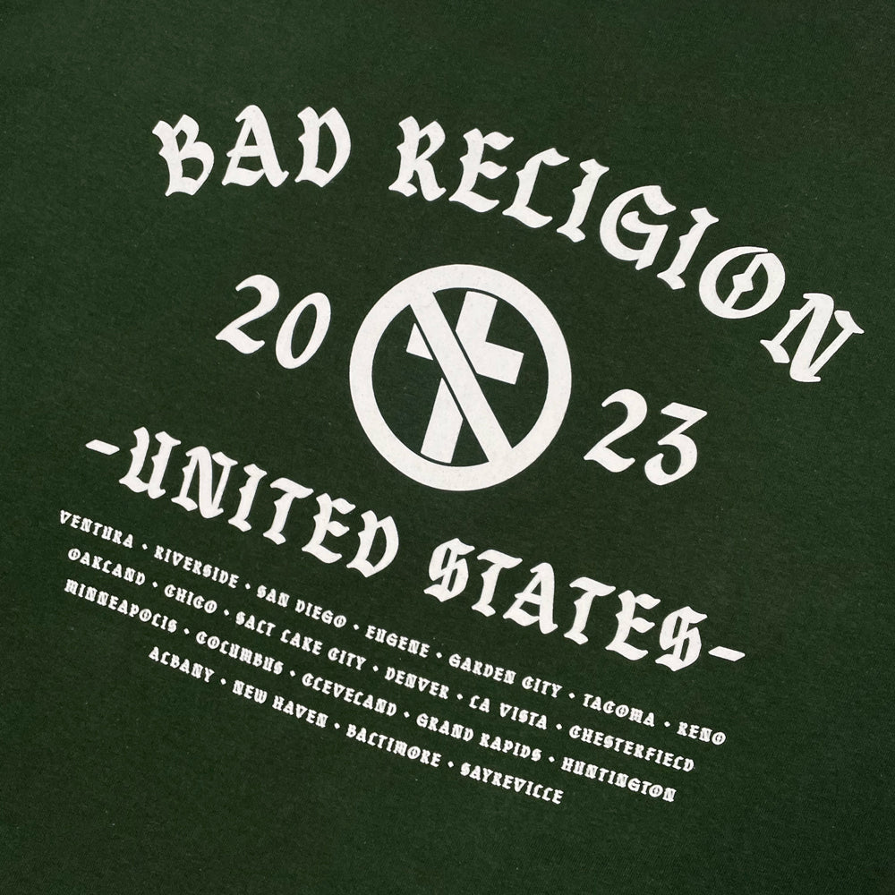 Close up of a back print of green Bad Religion tee with crossbuster logo and text reading "Bad Religion 2023 United States" followed by a list of cities from the 2023 tour
