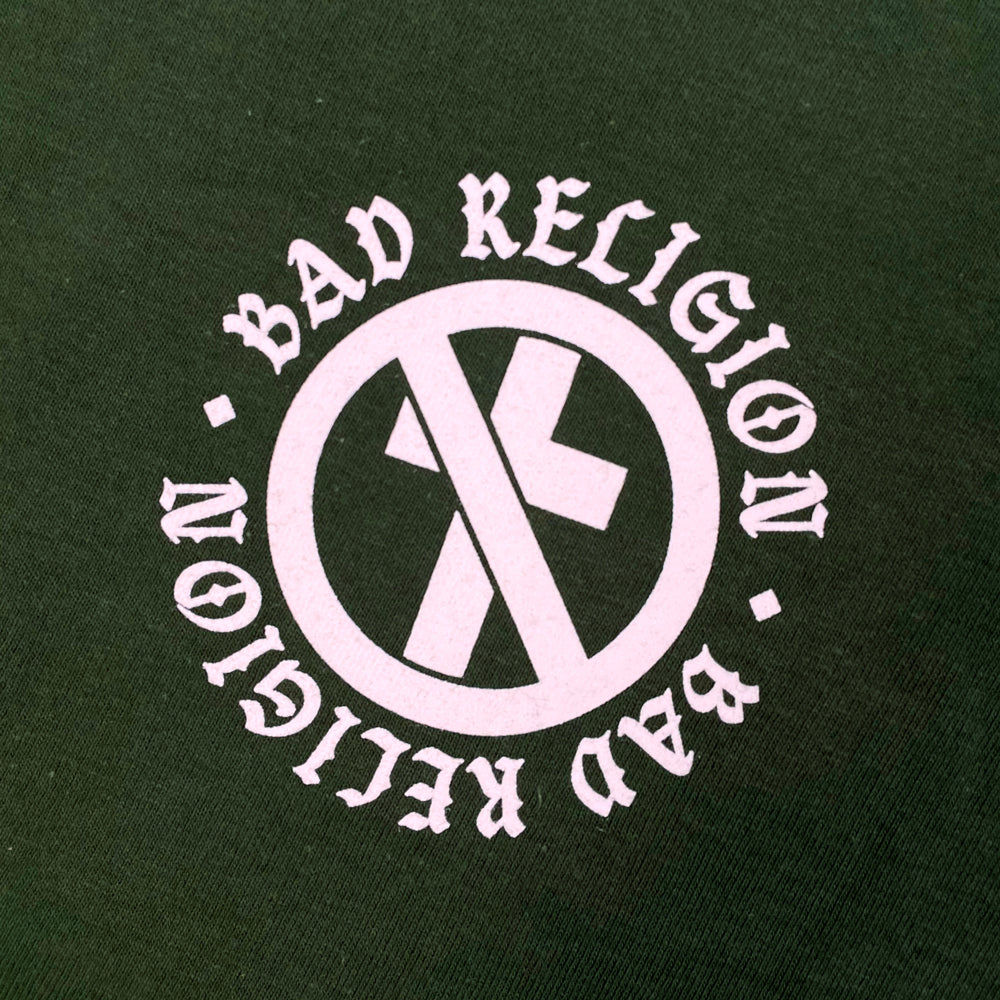 Close up of a front print of green Bad Religion tee with small crossbuster logo surrounded by text reading "Bad Religion Bad Religion"