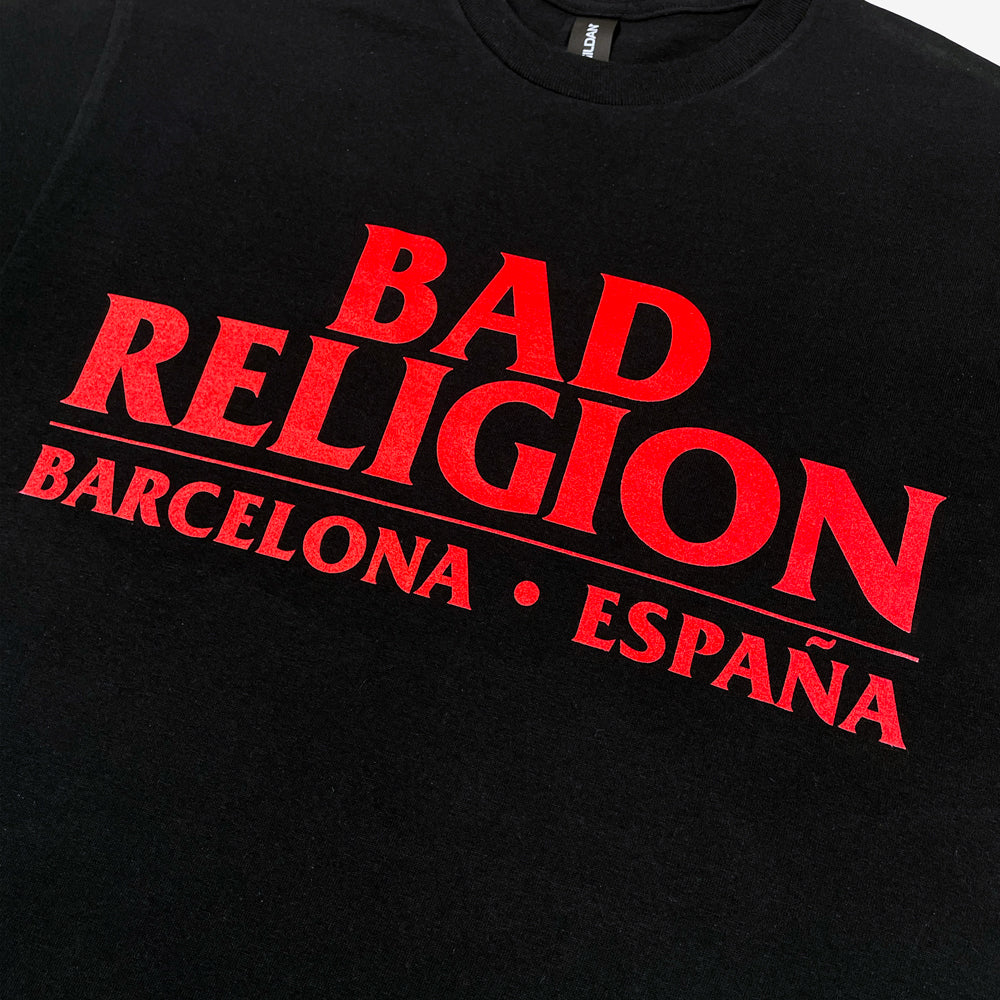 Close up of the front of a black tee against a white background with red text reading "Bad Religion, Barcelona, España"