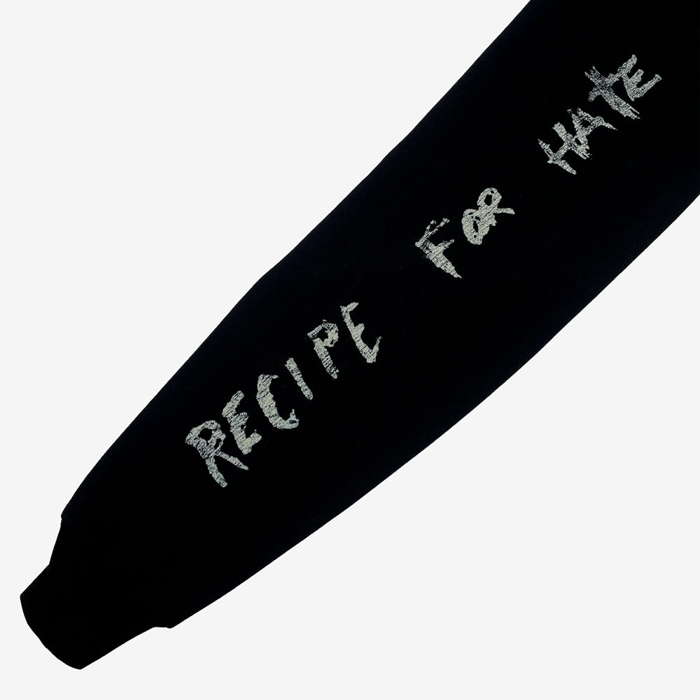 Close up of a black sweatshirt sleeve against a white background with text in light grey reading "Recipe for Hate."