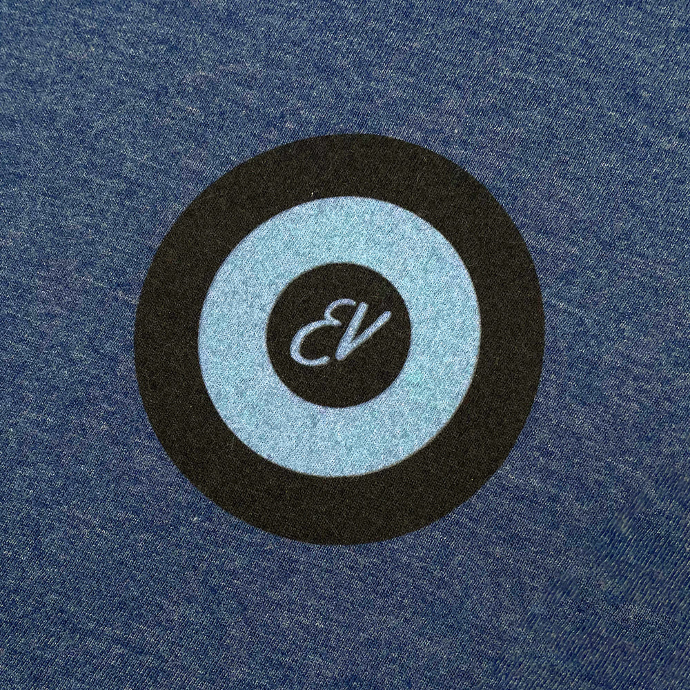 Close up of a heather denim tee against a white background with a black/light blue target design. In the center of the target is light blue letters reading "EV"