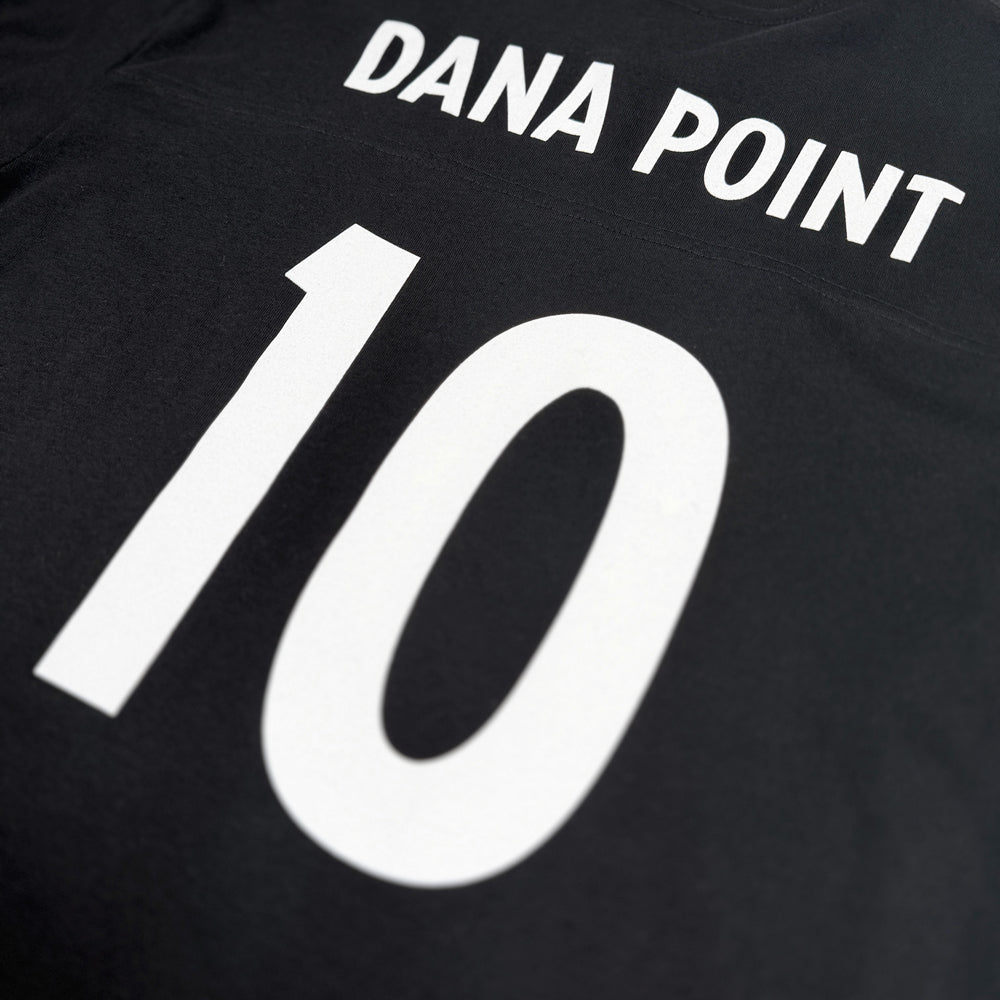 Close-up of white Dana Point and number 10 back graphic on black football tee