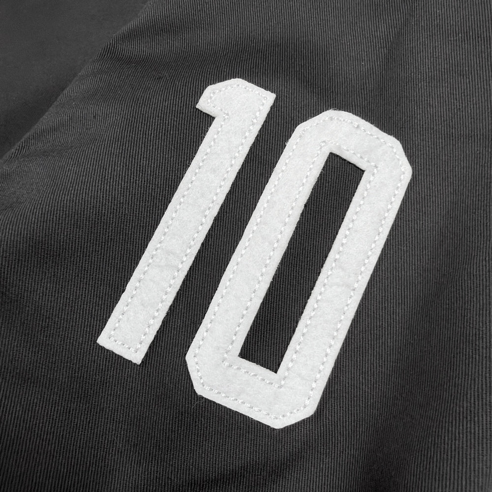 Close-up of white number 10 appliqué with visible stitching on black Eddie Vedder jacket sleeve
