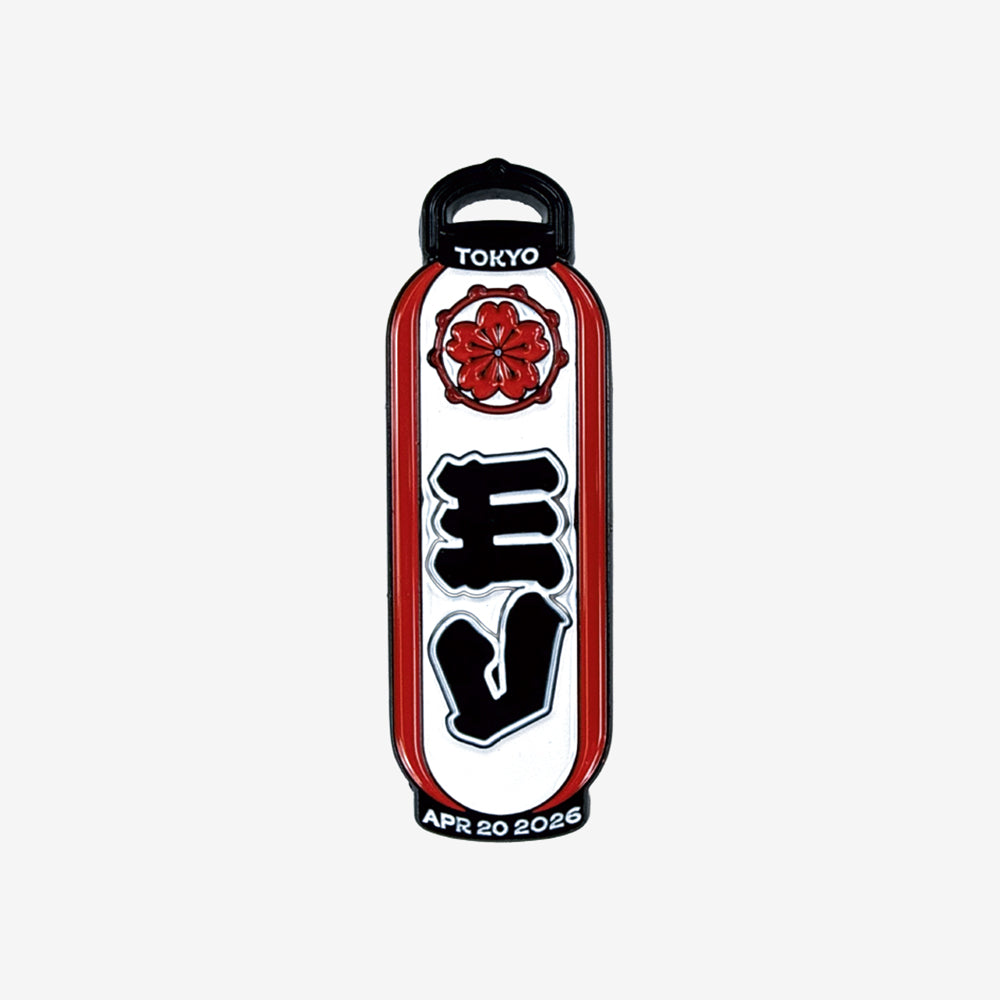An enamel pin against a white background that is a design of a white and red Japanese decorative lantern. In white text at the top it reads "Tokyo" and at the bottom it reads in white text "Apr 20 2026"