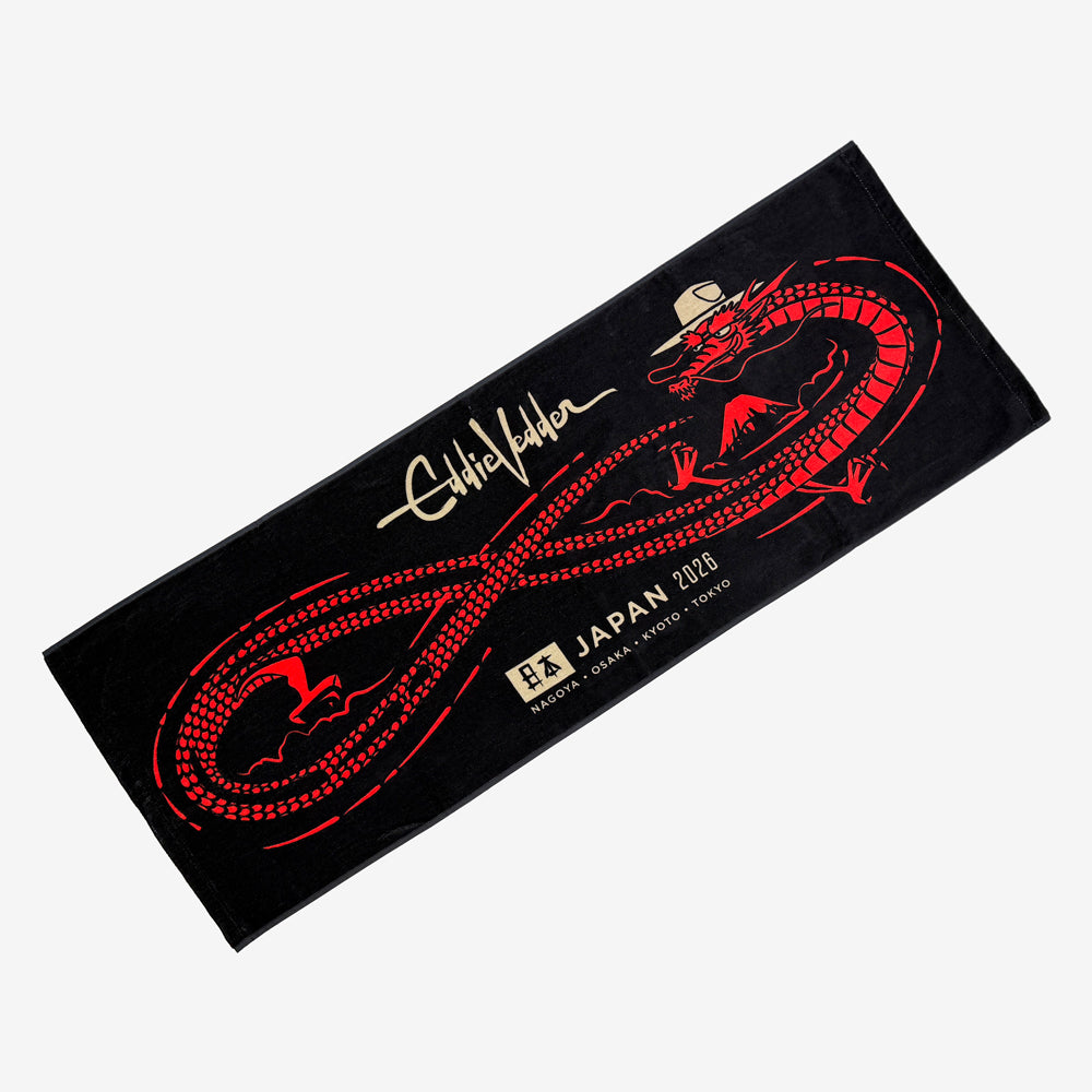 Black muffler towel against a white background with a red dragon design making a sideways 8 with its body. On top there is light beige text reading "Eddie Vedder" and at the bottom is light beige text reading "Japan 2026, NAgoya, Osaka, Kyoto, Tokyo"