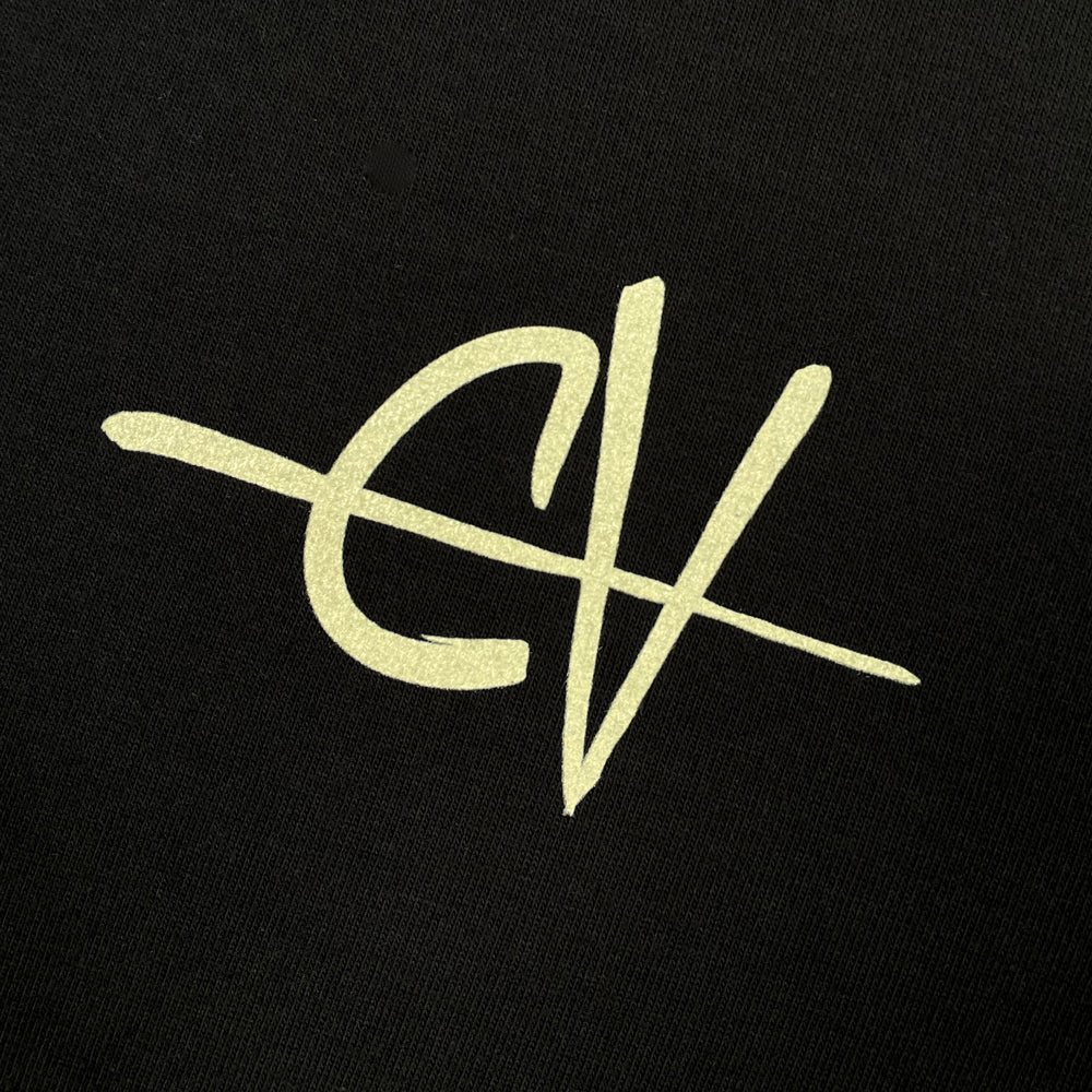 Close up of a black T shirt with a light beige text design on the chest of the letters "EV"