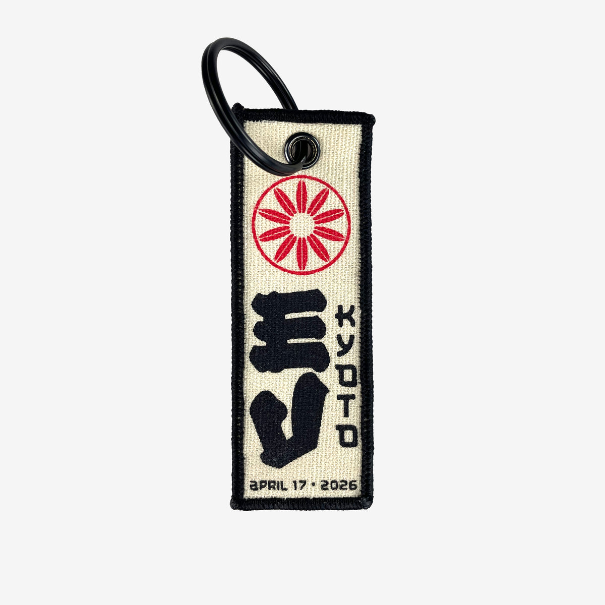 A flight tag keychain against a white background. At the top of the flight tag is a red circular design. In the middle is large black text reading "EV" and to the right of that is black text reading "Kyoto" At the bottom in black text there is a date that reads "April 17, 2026"