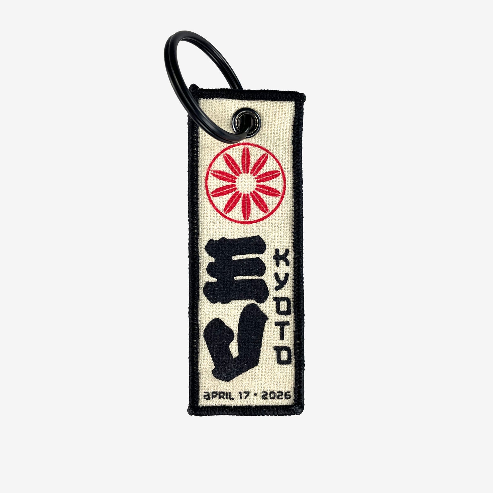 A flight tag keychain against a white background. At the top of the flight tag is a red circular design. In the middle is large black text reading "EV" and to the right of that is black text reading "Kyoto" At the bottom in black text there is a date that reads "April 17, 2026"