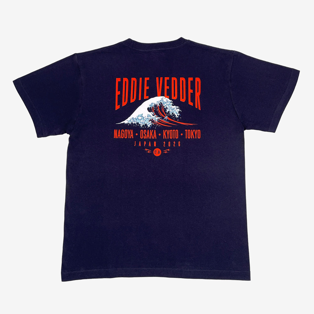Back of navy T shirt against a white background with red text reading "Eddie Vedder." Below that is a design of a great wave. Below the wave is more red text reading "Nagoya, Osaka, Kyoto, Tokyo, Japan 2026"