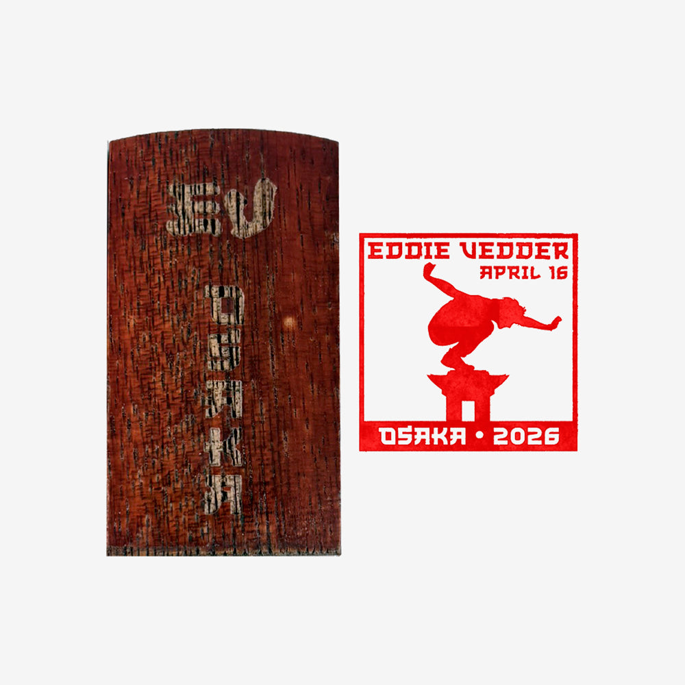 Wood stamp against white background with text that reads "EV Osaka" and to the right is a red stamp of a man balancing on Mt. Fuji with text that reads "Eddie Vedder April 16, Osaka 2026"