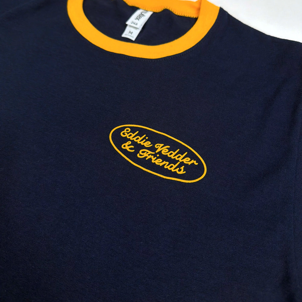 Close-up of Eddie Vedder & Friends oval chest graphic and yellow collar on navy Moto Club Tee