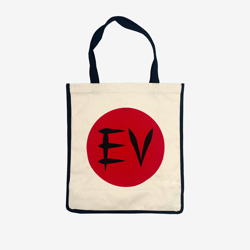 A natural tote bag with a black outline and black handles against a white background. In the center is a red circle and in the circle is black text reading "EV"