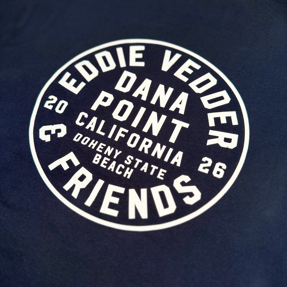 Close-up of white circular Eddie Vedder & Friends Dana Point graphic on navy hoodie