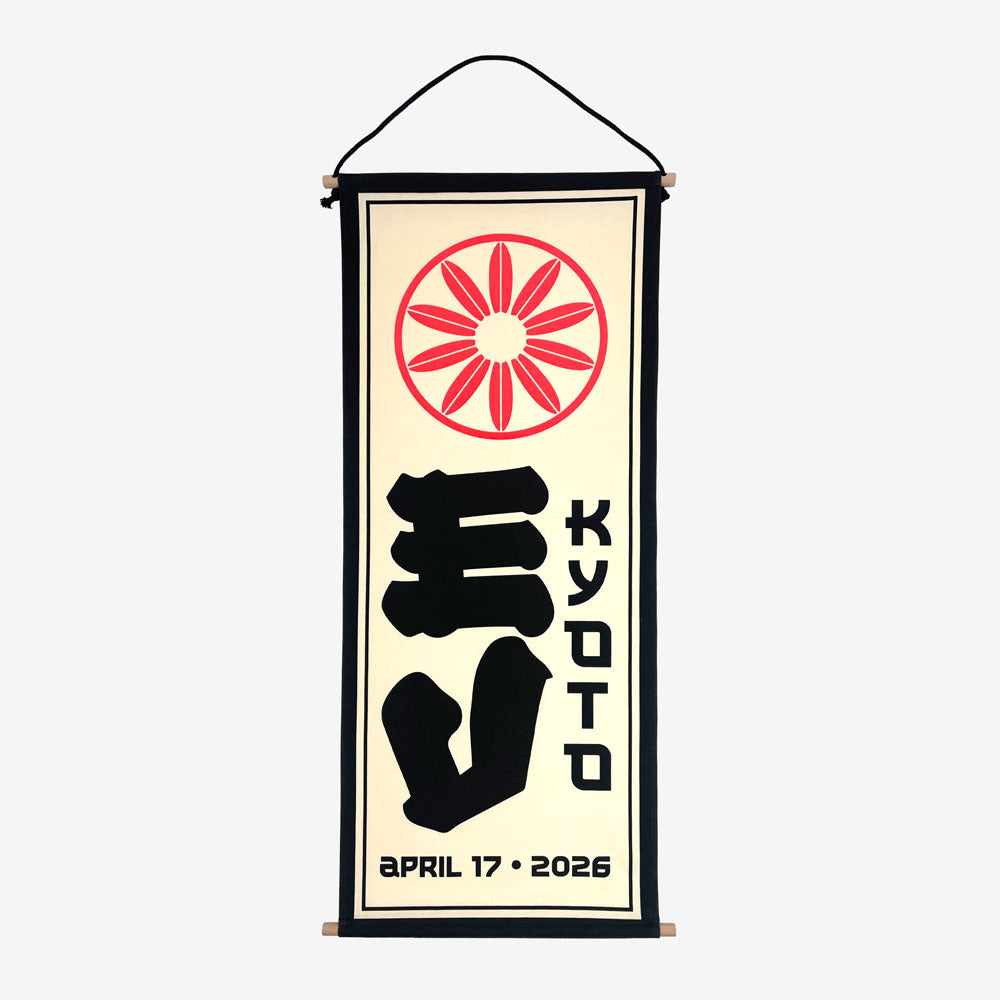 A wall scroll against a white background. At the top of the scroll is a light red circular design. In the middle is large black text reading "EV" and to the right of that is black text reading "Kyoto" At the bottom in black text there is a date that reads "April 17, 2026"