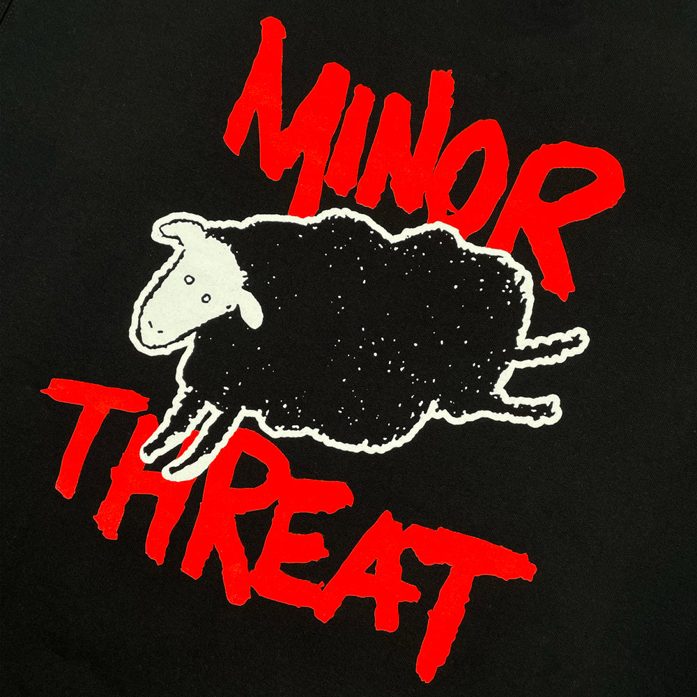 Close up of a black Minor Threat crewneck with illustration of a sheep around red text reading "MINOR THREAT"
