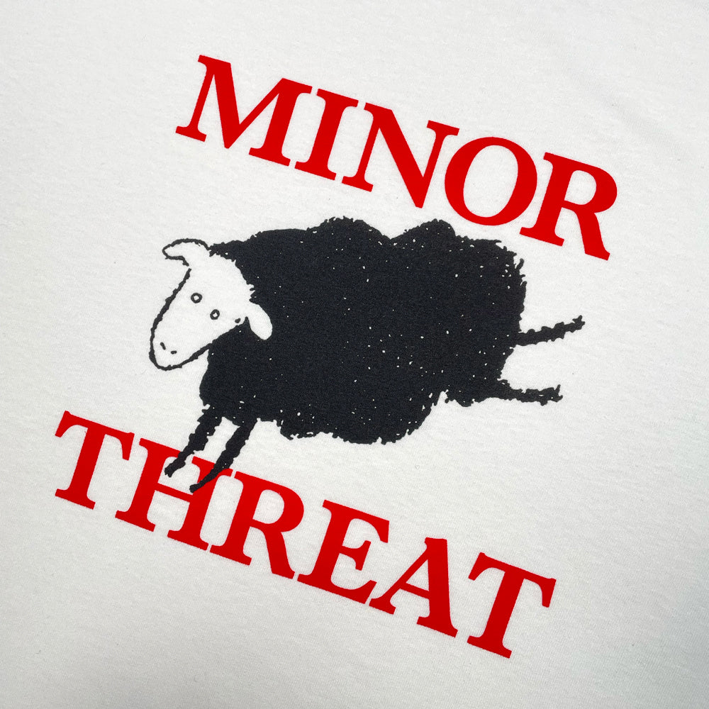 Close up of a white Minor Threat tee featuring the out of step sheep and red lettering that reads "MINOR THREAT"