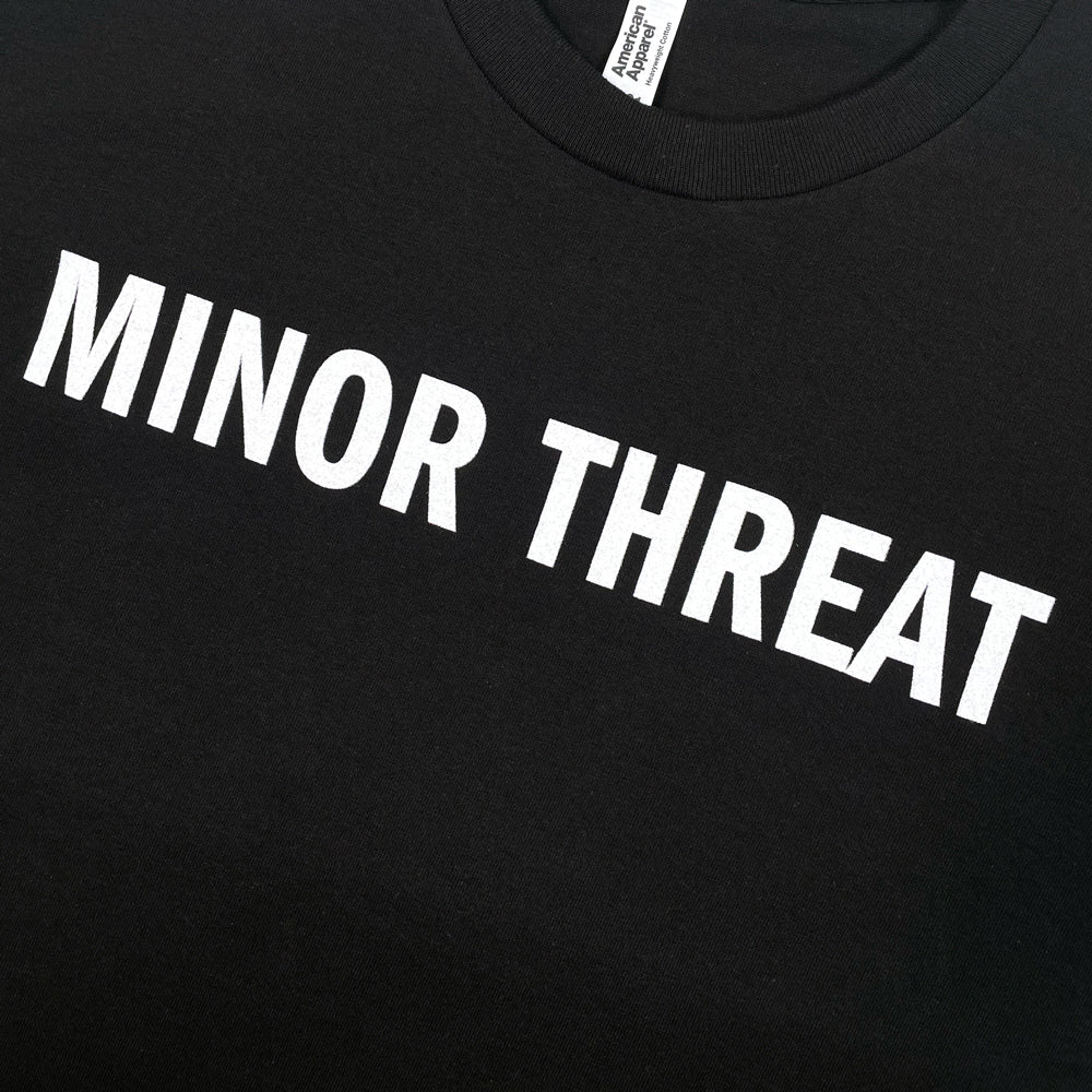 Close up of the front Print of black Minor Threat tee with typography reading "MINOR THREAT"