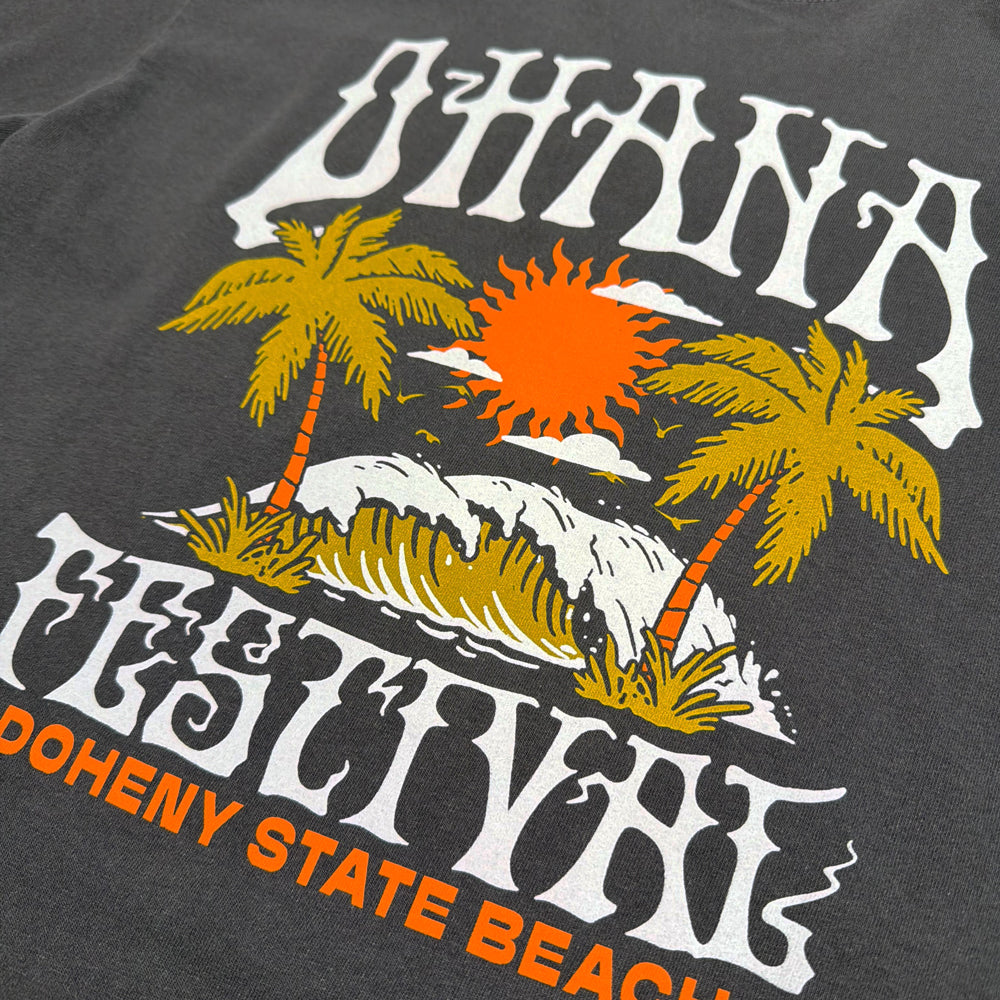Close-up of the palm trees, wave, and orange sun on the faded black Ohana Acid Wave Tee.
