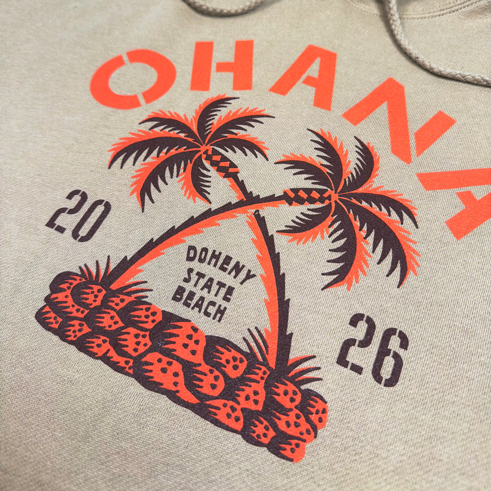 Close-up of crossed palms, Ohana lettering, and Doheny State Beach text on the sandstone hoodie.