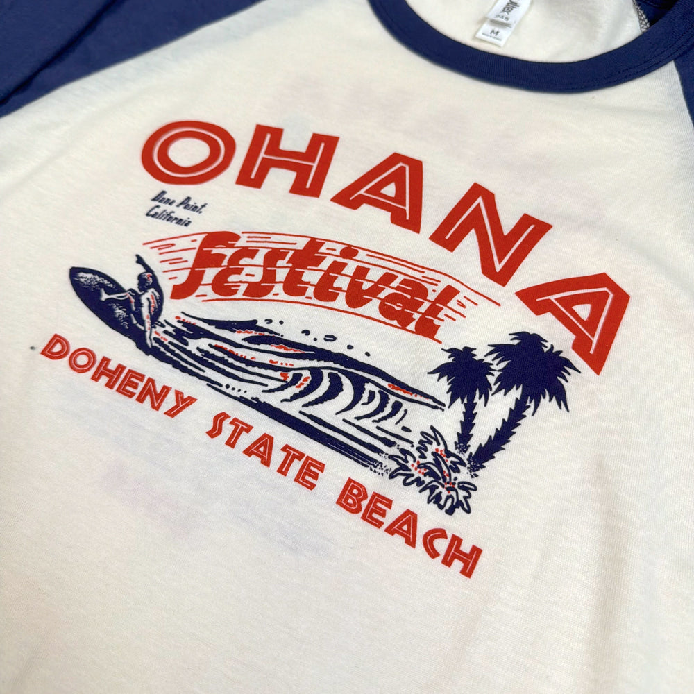  Close-up of red Ohana Festival lettering, a blue surfer and wave, and palm trees on the Surf Meet Tee.