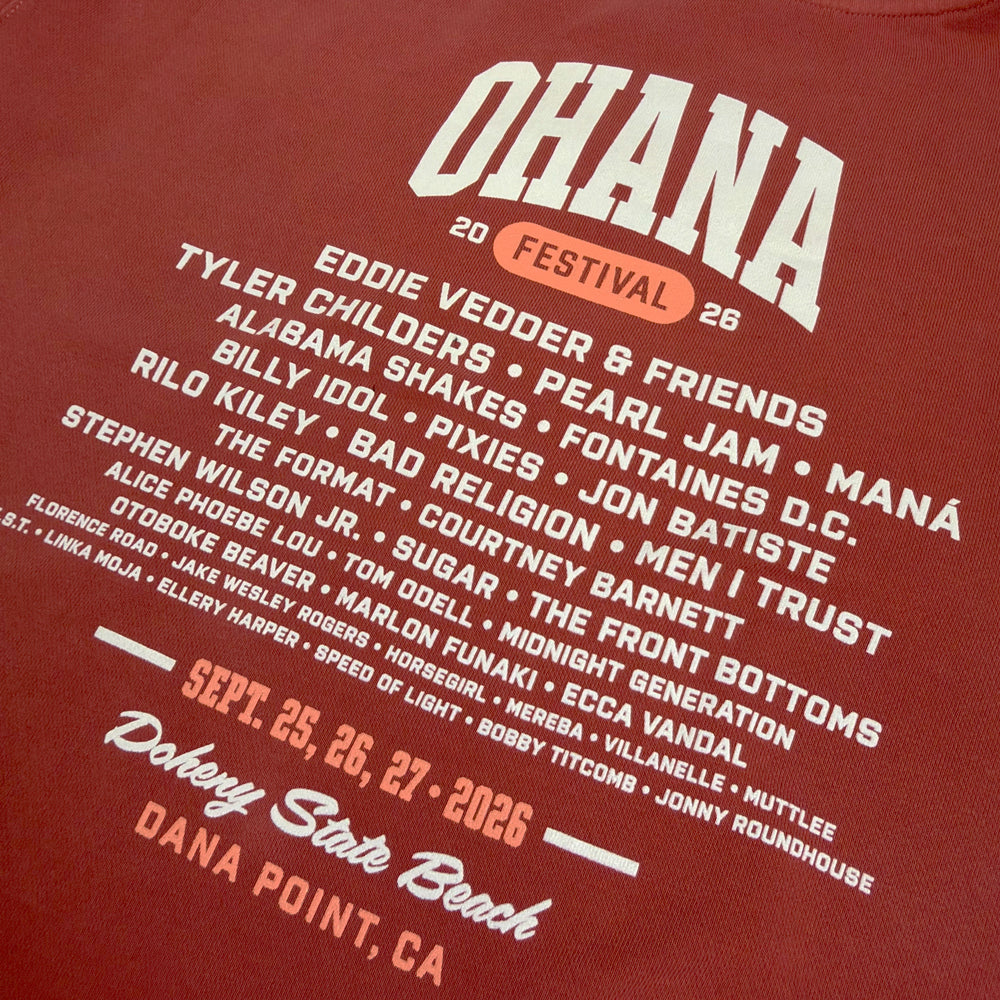 Close-up of the cream artist lineup, September 25–27, 2026 dates, and venue details on the amber crewneck’s back.