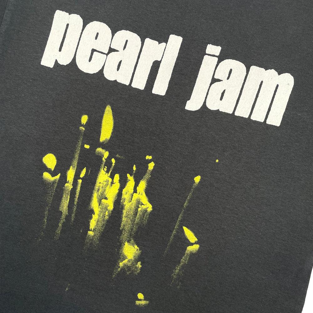Close up of a grey Pearl Jam Tee with yellow graphic of candles below lettering reading "Pearl Jam"