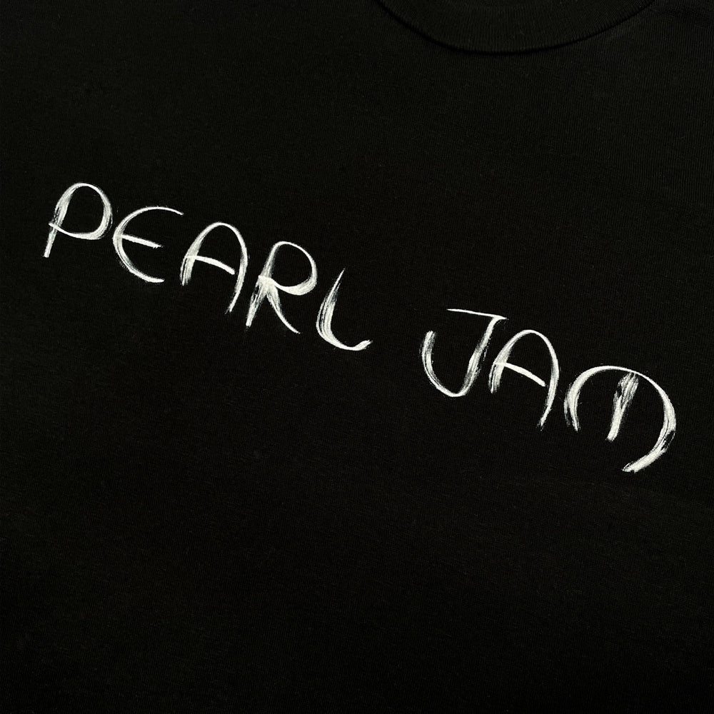 Close up of a black Pearl Jam tee front print with text reading "Pearl Jam"