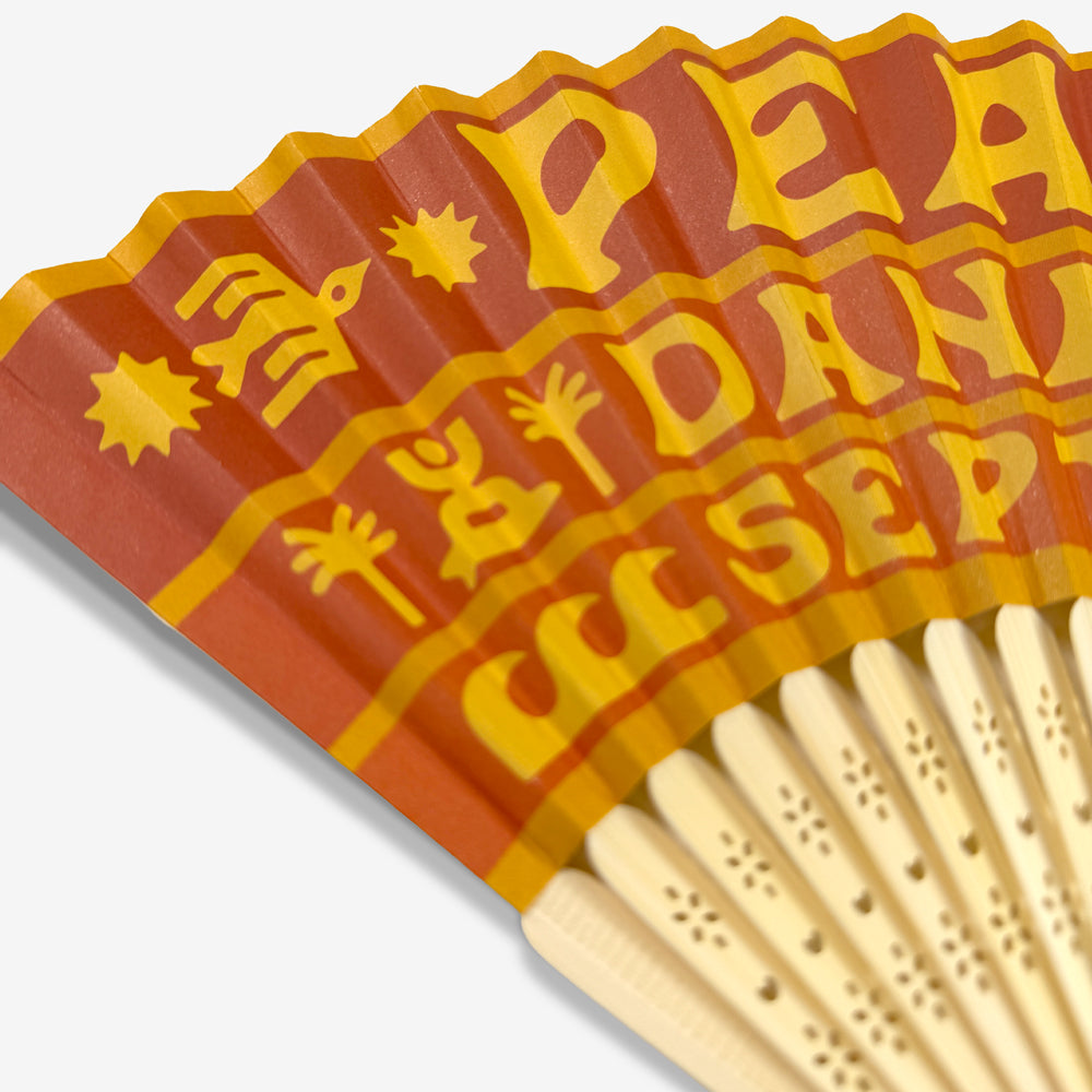 Close-up of orange and yellow Pearl Jam Dana Point artwork and decorative wood ribs on folding fan