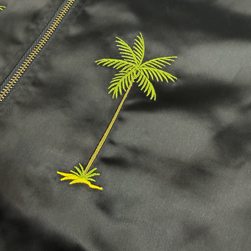 Close-up of embroidered green palm tree on black Pearl Jam satin jacket