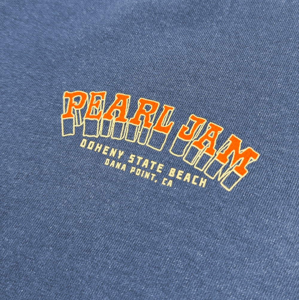 Close-up of orange and cream Pearl Jam Doheny State Beach chest graphic on faded navy tee