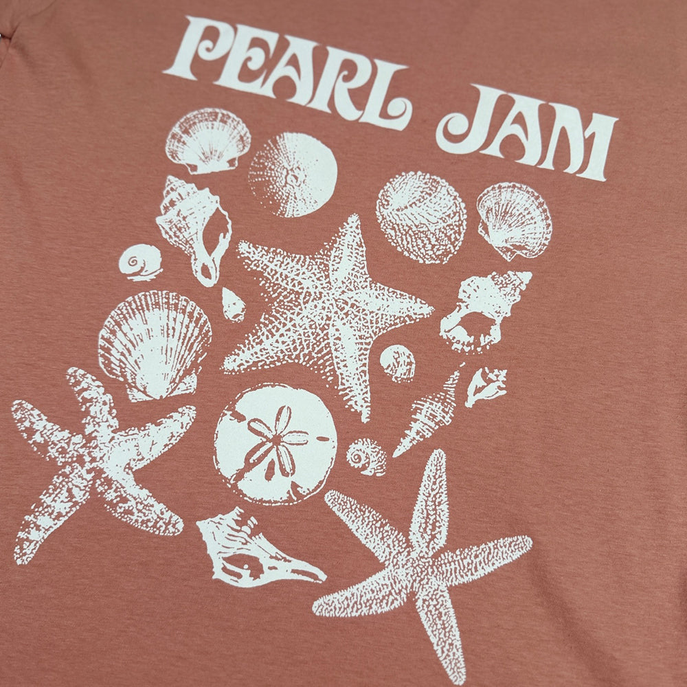 Close-up of white Pearl Jam seashell and starfish artwork on desert pink tee