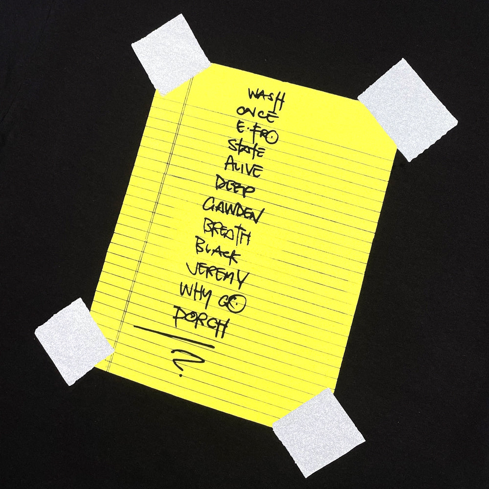 Close up of a black Pearl Jam t-shirt back print with graphic of a piece of notebook paper with list of Pearl Jam song titles