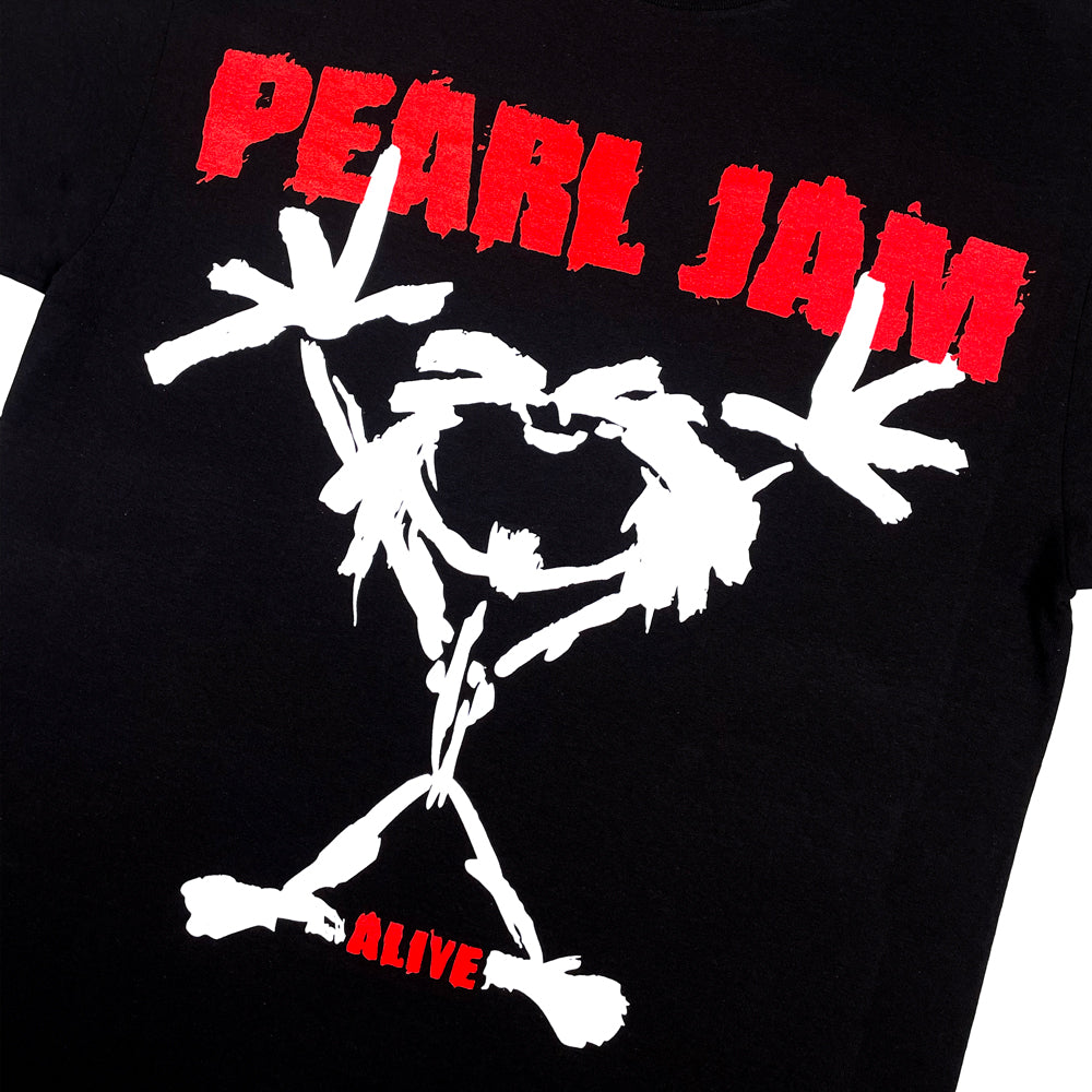 Close up of a black t-shirt front print with Pearl Jam Stickman graphic surrounded by red text which reads "Pearl Jam Alive"