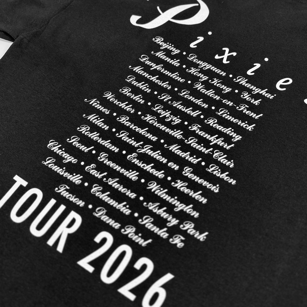 Close-up of white script listing Pixies tour cities, including Dana Point, above Tour 2026 text on black fabric.