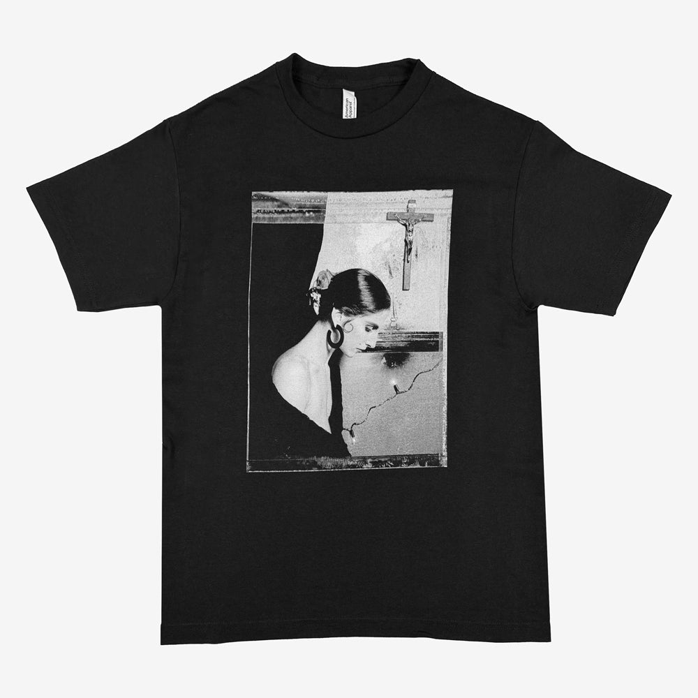 Black Pixies Framed Rosa Tee with a rectangular black-and-white portrait of a woman beneath a wall-mounted crucifix.