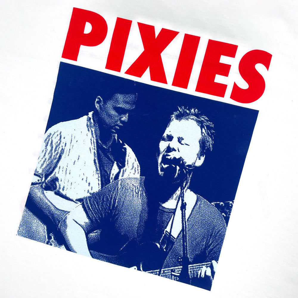 A close up of a white T Shirt that has red text reading "PIXIES" at the top with a blue photo design of the band performing.