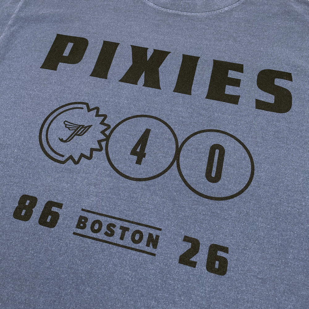 Close up of a blue Pixies t-shirt with black lettering reading "Pixies, P40, 86-26 Boston" against a white background