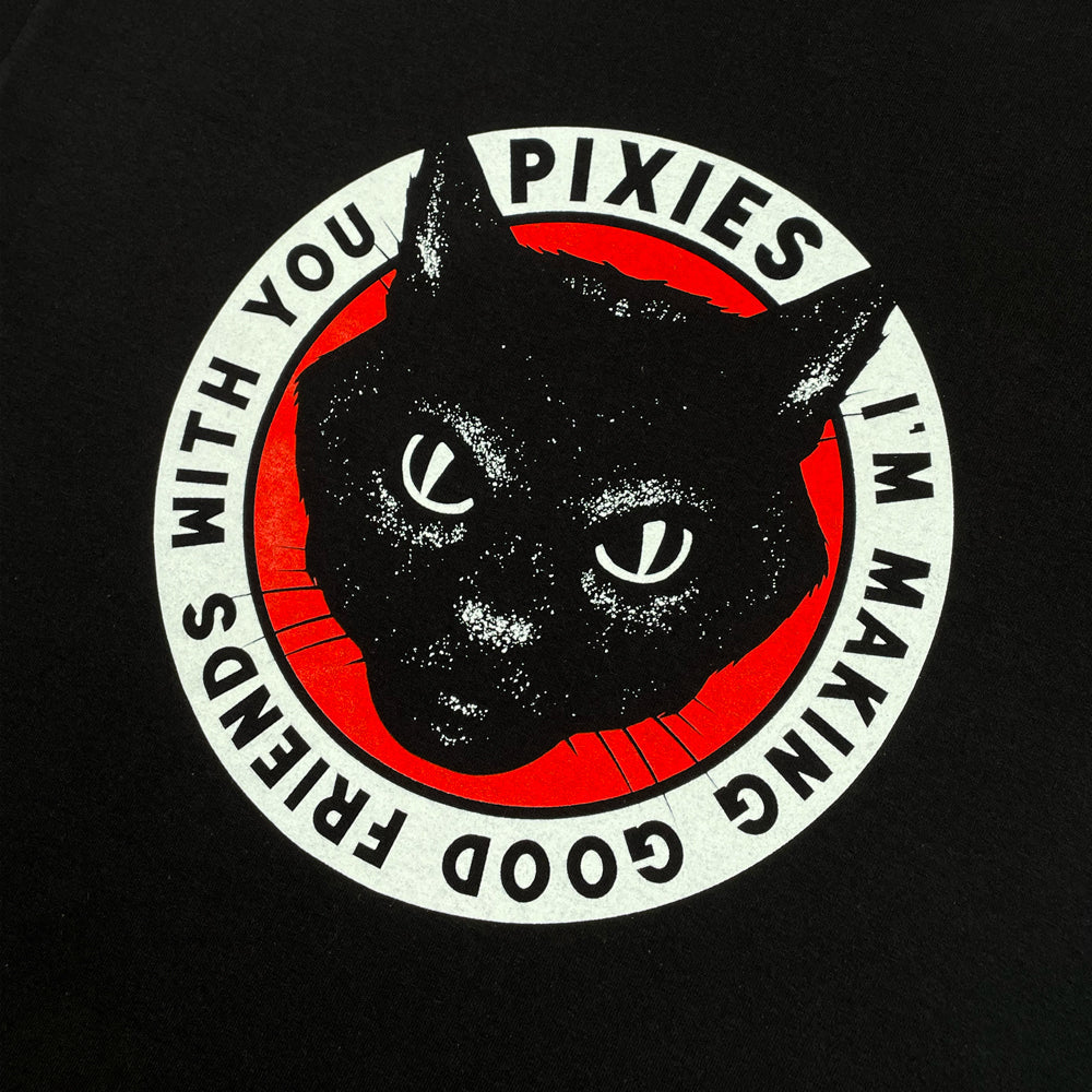 A black t shirt against a white background with a white circular design with black text reading "Pixies I'm making good friends with you." The inside of the circle is red and there is a design of black cat's head inside the circle.