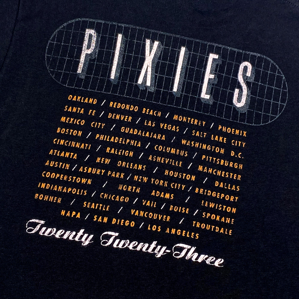 A close up of the back of a black t shirt with white text reading "Pixies" surrounded by a gray grid. Listed below the grid are all 2023 Tour dates, below the cities is white text reading "Twenty Twenty Three"